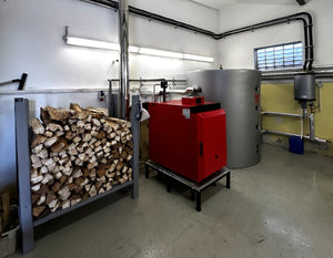 Holzvergaserkessel GK-7k-öko 🔥 in Heizungsraum mit Holzstapel und modernen Heizsystemen. Effiziente Heizlösung für umweltfreundliches Heizen.